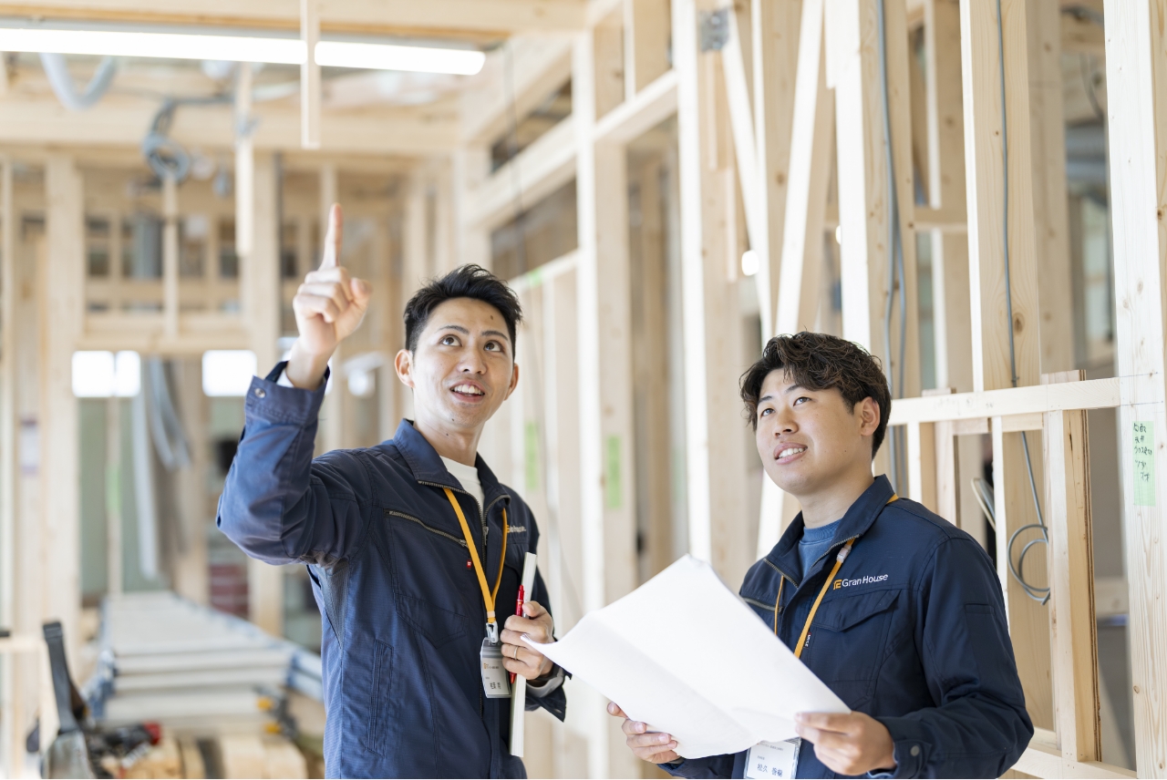 頭上を指さして指示している男性と同じ方向を見上げているもう一人の男性