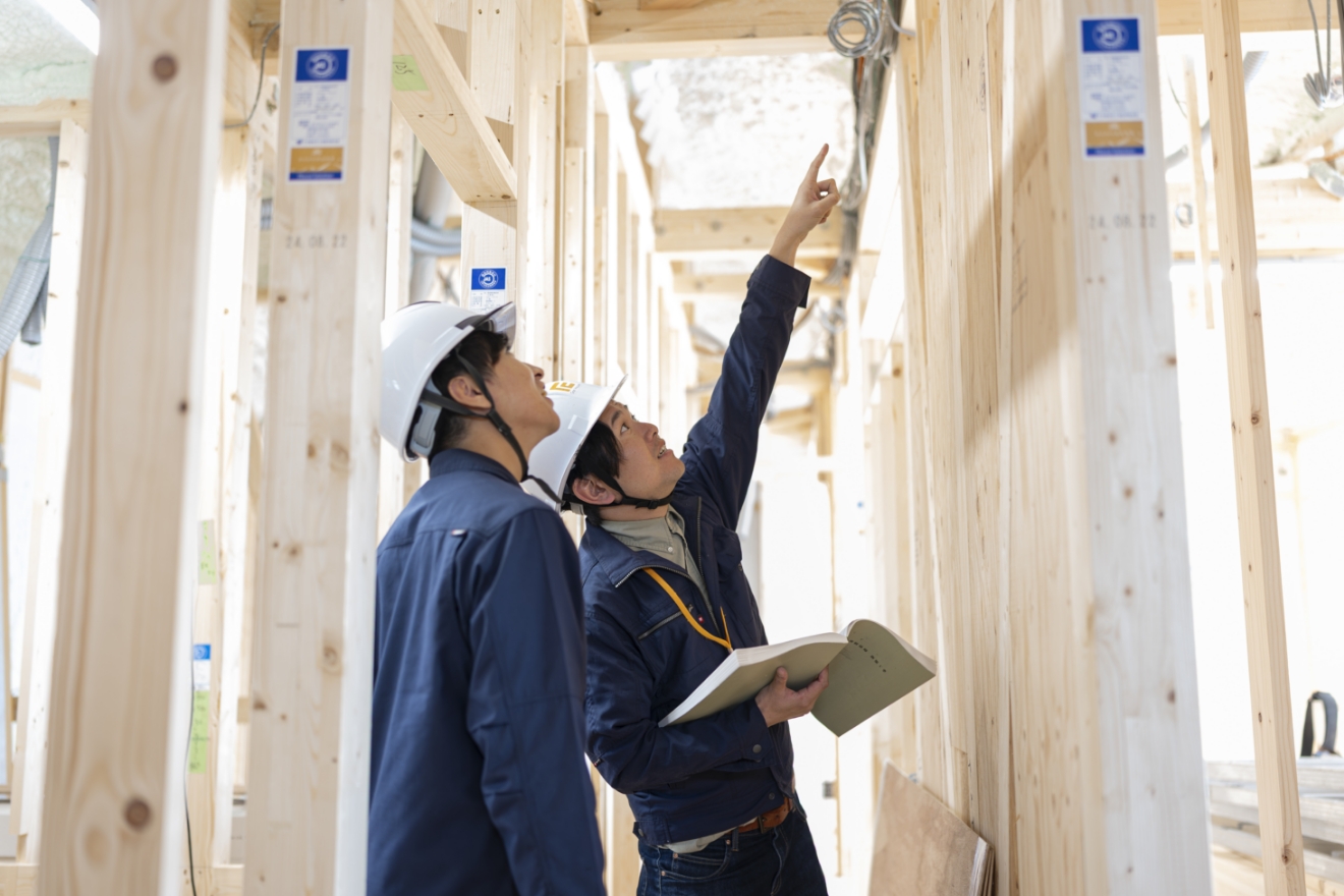 頭上を指さして指示をしている男性とそれを隣で見ている男性