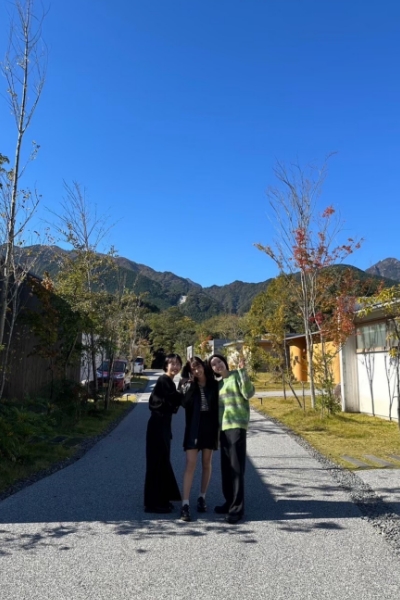 青空の下、笑ってこちらにピースをしている3人の女性