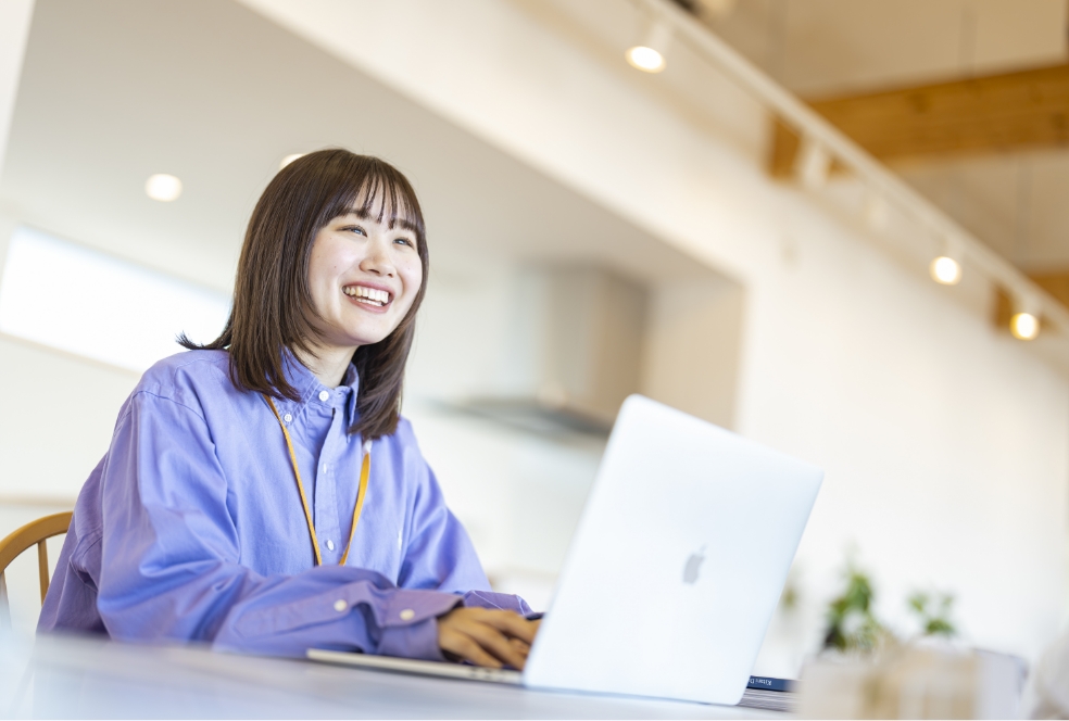 パソコンで作業しながら笑いかけている女性社員