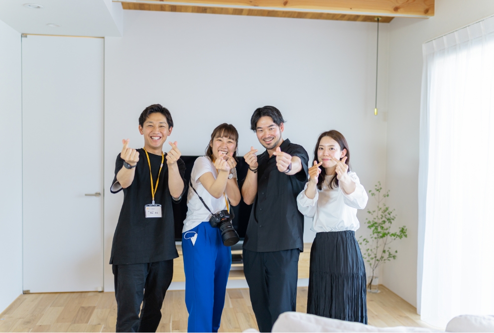 指ハートをしている男女4人の社員