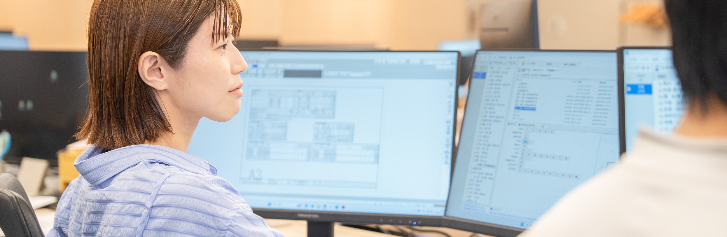 複数のパソコン画面で作業をしている実施設計担当の女性
